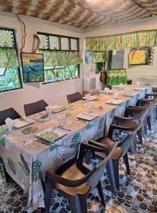 a room with a long table and chairs and windows at Pension Mitiana in Tatoi
