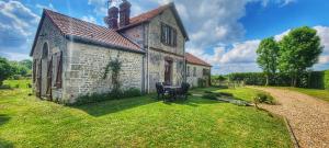 an old building with a table and chairs in the yard at Gîte du Grand frêne in Orrouy
