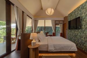 a bedroom with a bed and a large window at J Valley Resort in Pong Yaeng