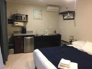 a bedroom with a bed and a kitchen with a microwave at The Pier Beach Inn & Suites in Willemstad