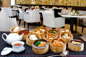 a table with bowls of food and cups of tea at Classic Kameo Hotel & Serviced Apartment, Rayong in Rayong