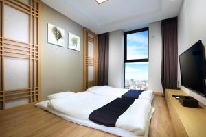 a bedroom with a large bed and a flat screen tv at Hotel The One in Jeju