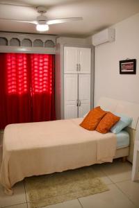 a bedroom with a bed with red curtains at Grapes of Grace3 in Baie Nettle
