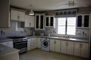 a kitchen with white cabinets and a washer and sink at Grapes of Grace3 in Baie Nettle