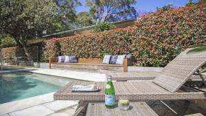 a bottle of wine sitting on a chair next to a pool at Pool, Pet - Friendly, Fireplace, Walk To Beach in Pearl Beach