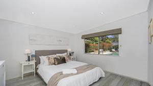 a white bedroom with a bed and a window at Pool, Pet - Friendly, Fireplace, Walk To Beach in Pearl Beach