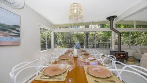 a dining room with a long wooden table and white chairs at Pool, Pet - Friendly, Fireplace, Walk To Beach in Pearl Beach