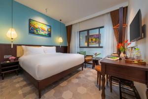a hotel room with a large bed and a desk at BACKHOME BOUTIQUE Old Town Hoi An in Hoi An