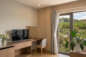 a room with a desk with a television and a window at Gold View Boutique Hotel Đà Lạt in Da Lat