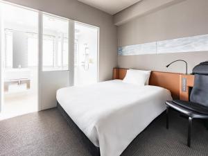 a bedroom with a large white bed and a chair at remm Shin-Osaka in Osaka
