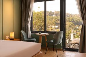 a hotel room with a bed and chairs and a window at Gold View Boutique Hotel Đà Lạt in Da Lat