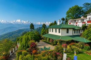 a building with a green roof with mountains in the background at Sterling Park Kalimpong in Kalimpong
