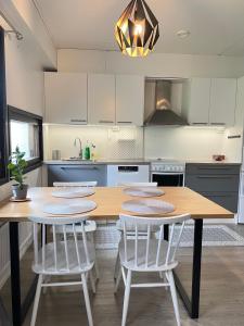 a kitchen with a wooden table and white chairs at Saunallinen kolmio kahdella autopaikalla in Jyväskylä