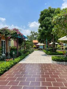 a brick walkway in a park with trees and flowers at Melalueca tay ninh in Tây Ninh