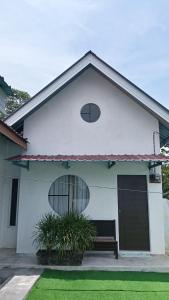 a white house with a bench in front of it at Rembulan Guesthouse in Mersing