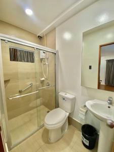 a bathroom with a shower and a toilet and a sink at Commander Suites de Velada in Antipolo +30 photos