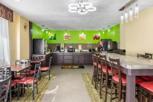 a kitchen with green walls and tables and chairs at Quality Inn Grand Rapids Near Downtown in Grand Rapids