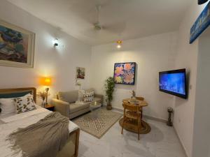 a room with a bed and a couch and a tv at Kai Apartments Near Airport Zanzibar in Zanzibar City