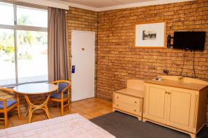 a hotel room with a bed and a table and a tv at Nandewar Motor Inn in Narrabri