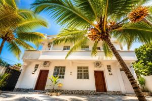 a white house with palm trees in front of it at Kai Apartments Near Airport Zanzibar in Zanzibar City