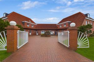 a house with a white gate and a brick driveway at elf-36 Apartmenthaus Bensersiel in Bensersiel
