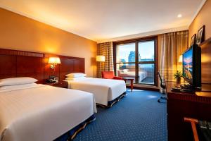 a hotel room with two beds and a television at Shanghai Qilu Hotel in Shanghai