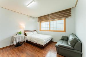 a bedroom with a bed and a couch and a window at U&I Pension in Yangyang