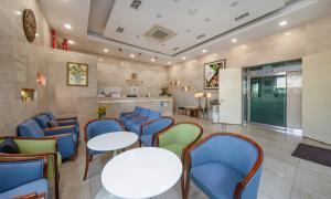 a waiting room with tables and blue chairs at Mud Beach Hotel in Boryeong