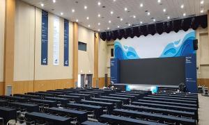 a lecture hall with rows of tables and a screen at Mud Beach Hotel in Boryeong