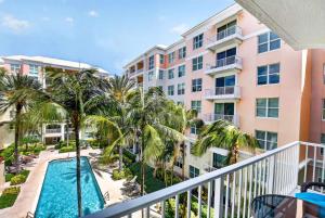 an apartment balcony with a swimming pool and palm trees at Moorings Pool Overview Resort in Lantana