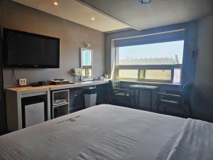 a bedroom with a bed and a desk and a television at Ocean View Haute Hotel in Busan