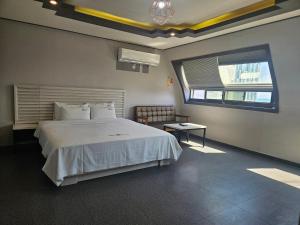 a bedroom with a large white bed and a window at Ocean View Haute Hotel in Busan