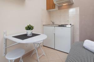 a small kitchen with a table and a white refrigerator at Apartments Barbarić in Zaostrog