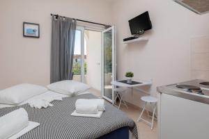 a small white room with a bed and a kitchen at Apartments Barbarić in Zaostrog +41 photos