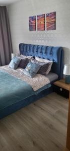 a bed with a blue headboard in a bedroom at Apartamentai AGNIJA in Kretinga