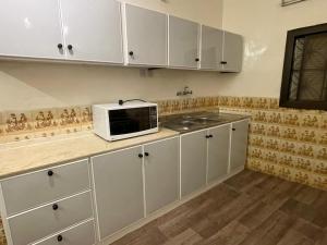 a kitchen with white cabinets and a microwave on a counter at بيت لانا in Abha