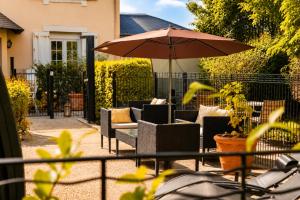 a patio with chairs and an umbrella at Hôtel Villa Flornoy Pornichet Baie de la Baule in Pornichet