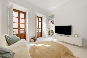 a white living room with a tv and a couch at Casa Miclá in Lagos
