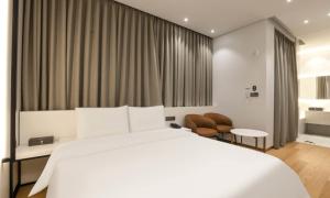 a bedroom with a white bed and a large window at Uiwang Milos Hotel in Uiwang
