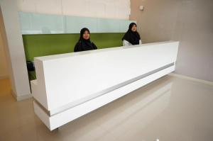 two women standing behind a large white counter in a room at Kosma Business Hotel in Kuantan