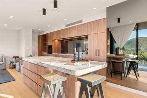 an open kitchen with a large island with stools at Casa Celeste, Grand Architectural Residence in Wollongong