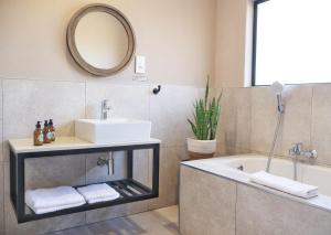 a bathroom with a sink and a tub and a mirror at Symponia Guesthouse in Khanzi +21 photos