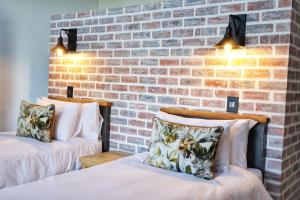 two beds in a room with a brick wall at Symponia Guesthouse in Khanzi