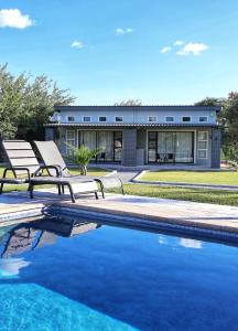 a swimming pool with two benches next to a house at Symponia Guesthouse in Khanzi