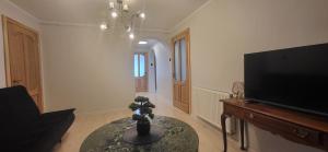 a living room with a table and a flat screen tv at Apartamentai AGNIJA in Kretinga