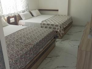 two beds in a room with marble floors at Hotel Shankar Place in Khātu