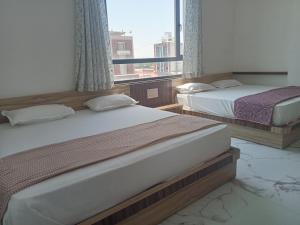 two beds in a room with a window at Hotel Shankar Place in Khātu