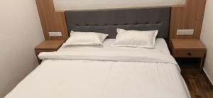a bed with white sheets and pillows in a room at Hotel Midtown in Rourkela