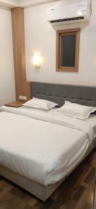 a white bed in a room with a window at Hotel Midtown in Rourkela
