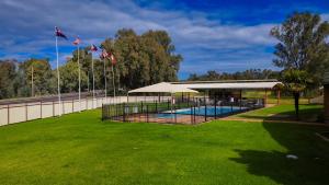 a swimming pool with a pavilion in a grass field at Nandewar Motor Inn in Narrabri